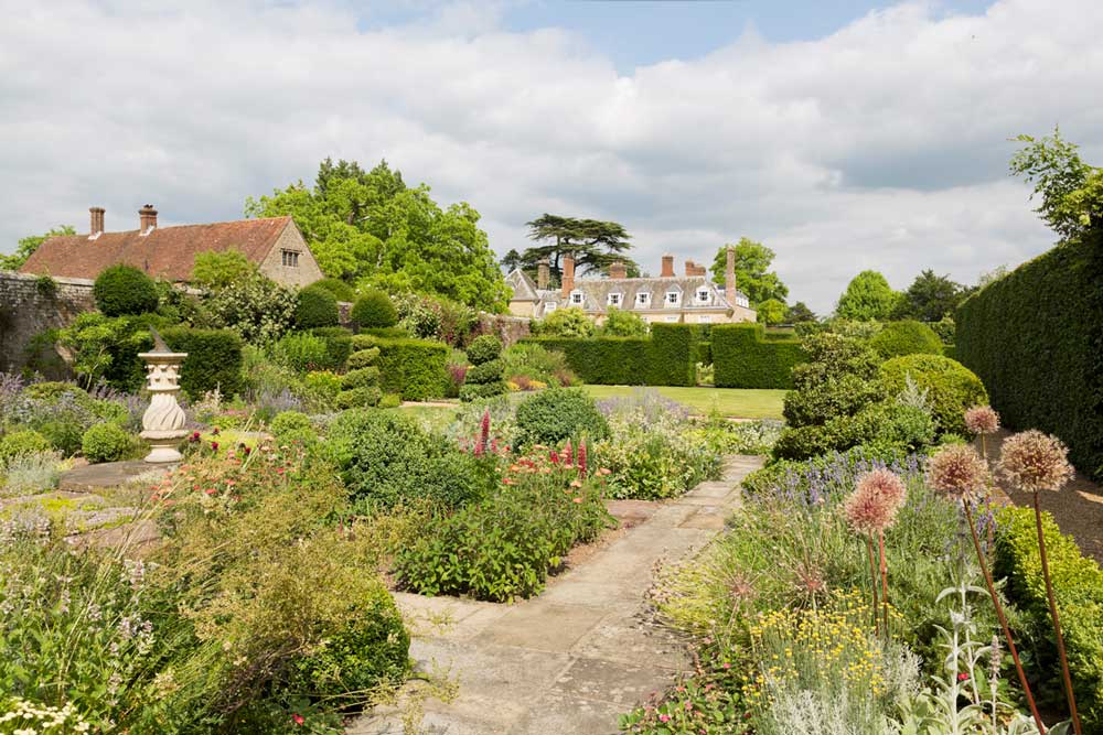Woolbeding-Garden,-view-of-garden-topiary-and-house,-credit-National-Trust